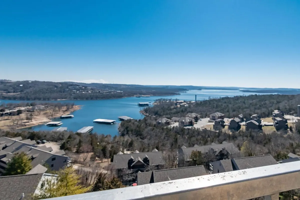 This image captures a beautiful view of Table Rock Lake, marinas, houses, and a forested area beneath a wide sky. The tranquil scene highlights the natural beauty and outdoor recreation opportunities near the penthouse.