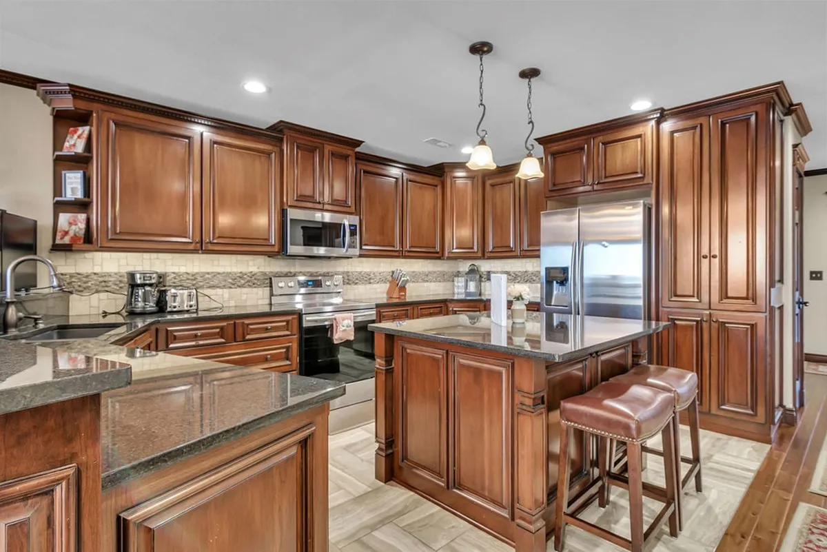 A gourmet kitchen with dark wooden cabinetry, a central island with seating, gleaming granite countertops, and stainless steel appliances. The kitchen exudes warmth and sophistication, perfectly suited for entertaining and preparing meals for loved ones.