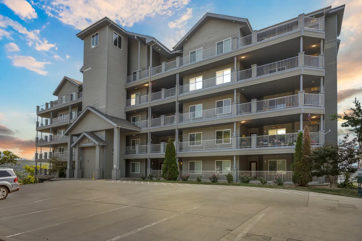 This image shows the inviting exterior of the property, with balconies overlooking the landscaped grounds, the building’s entrance, and a welcoming courtyard. The scene evokes the promise of sunset views and opportunities for socializing or enjoying quiet moments outdoors.