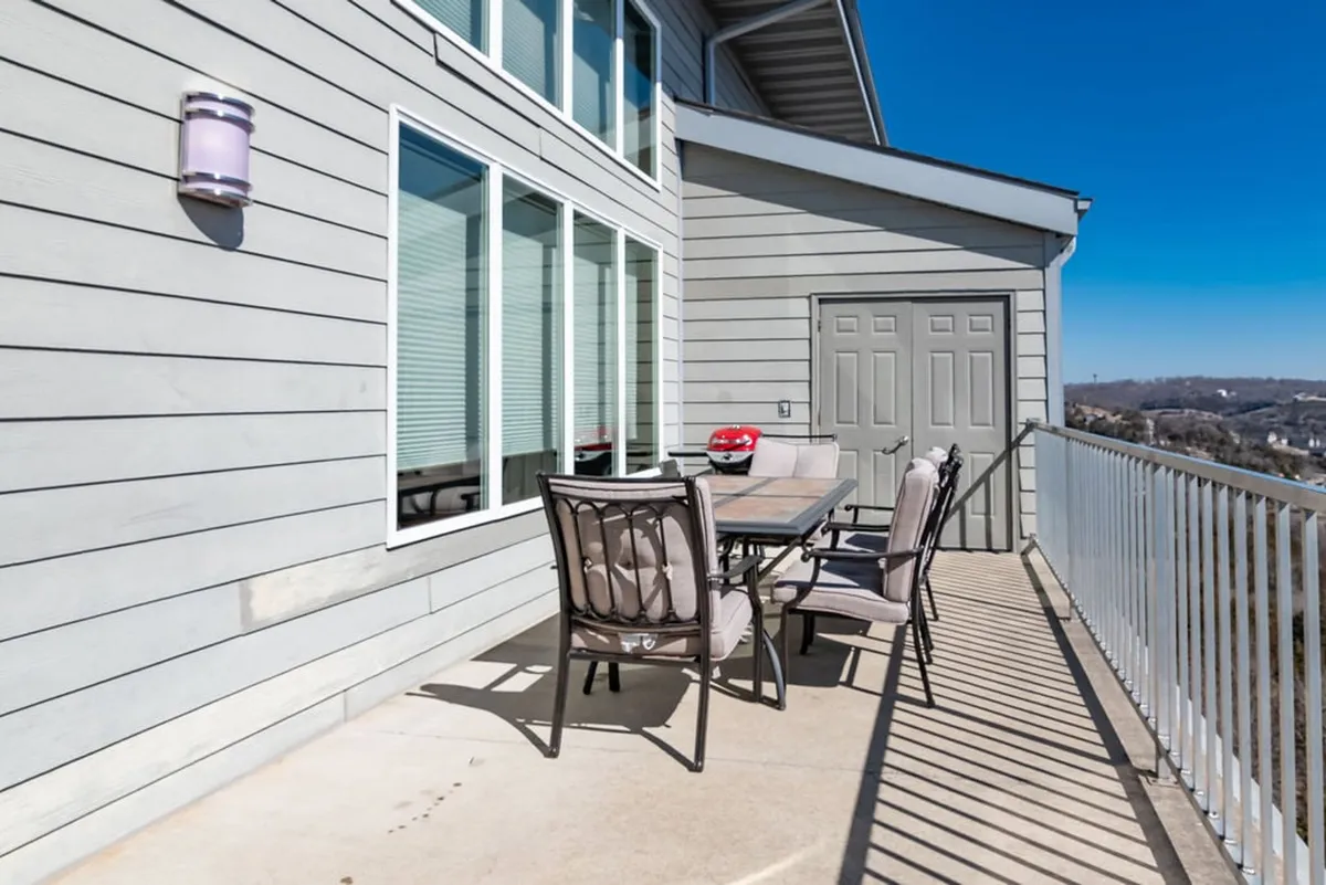 An outdoor deck furnished with a dining table and chairs, offering commanding views over the lake and distant hills. The space is ideal for al fresco dining, relaxing with morning coffee, or toasting the sunset, perfectly extending the gathering spaces outdoors.