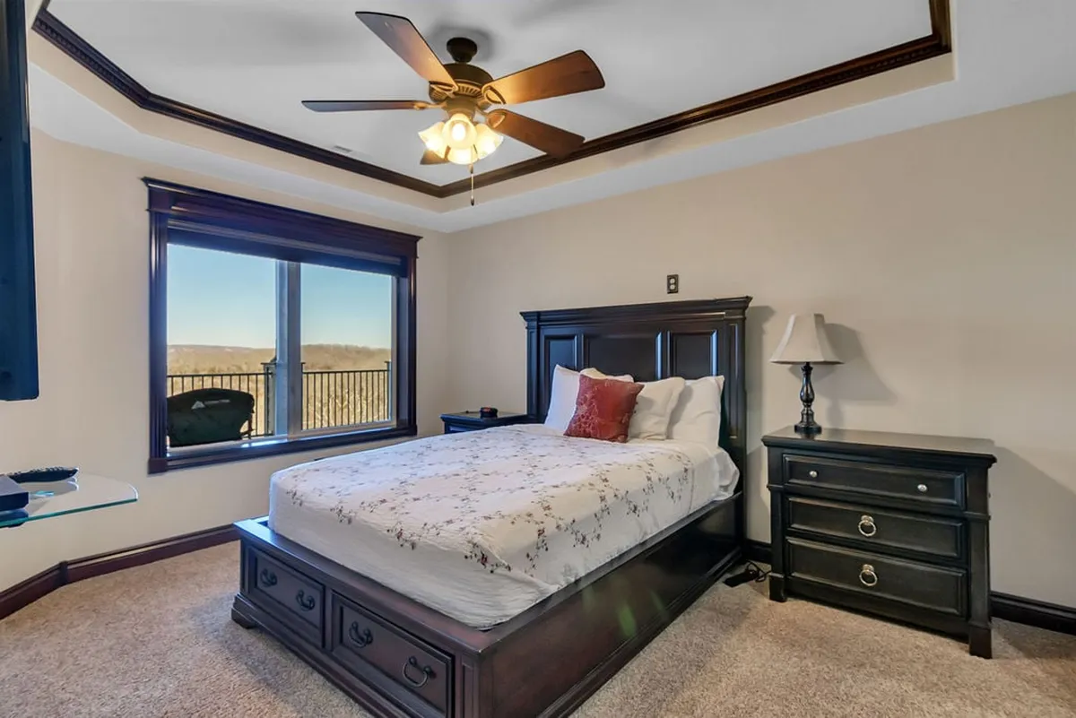 A serene bedroom with floral bedding, a large window allowing in natural light and offering beautiful views, and dark wood furniture creating a warm and inviting atmosphere. The space feels private and well-appointed, perfect for restful nights or leisurely mornings.